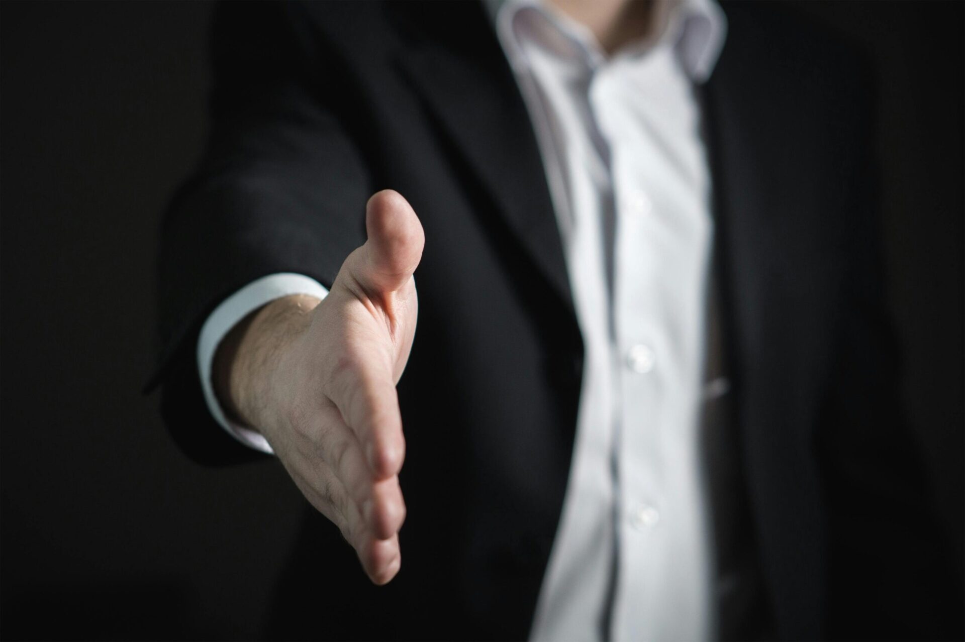 Sofort Autonkauf Close-up of a businessman extending hand for a handshake, symbolizing agreement and partnership.